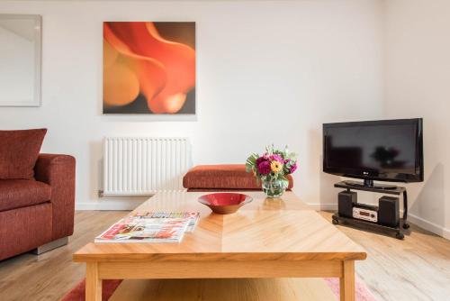 a living room with a coffee table and a tv at PREMIER SUITES Newcastle in Newcastle upon Tyne