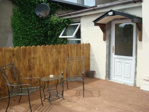 two chairs and a table in front of a fence at Swinford Bridge Street Apartment in Swinford