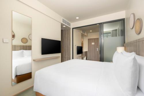 a bedroom with a white bed and a television at Staybridge Suites Bangkok Sukhumvit by IHG in Bangkok