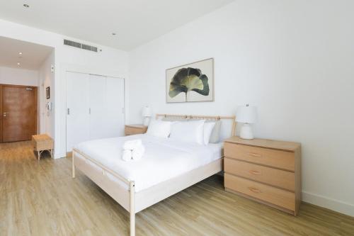 a bedroom with a white bed and a wooden dresser at Stylish Studio in Al Barza hosted by Voyage in Abu Dhabi