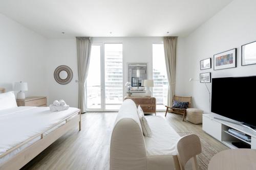a white bedroom with a large bed and a tv at Stylish Studio in Al Barza hosted by Voyage in Abu Dhabi