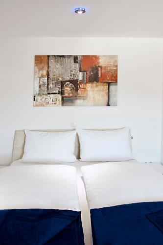 two beds in a room with a painting on the wall at Hotel Garni Ammergauer Hof in Oberammergau