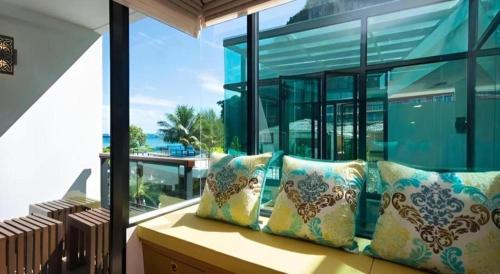 a bench with pillows sitting in front of a window at Phi Phi Nice Beach Hotel Hip in Phi Phi Don