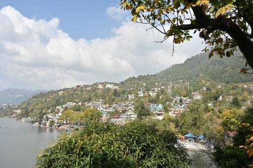 a town on a hill next to a body of water at Joeys by the Lakeside in Bhīm Tāl