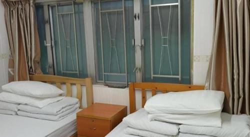 two twin beds in a room with green windows at New Mong Kok Guest House in Hong Kong
