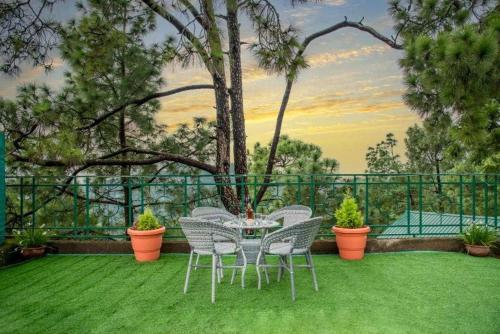 a patio with a table and chairs on the grass at ExoticStays l Empire Kasauli in Kasauli