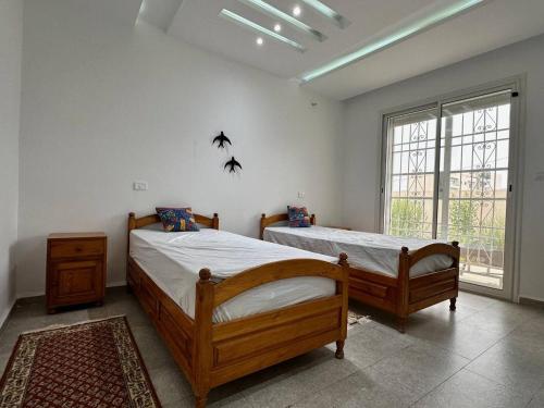 Un dormitorio con dos camas y una ventana. en Villa Azur, en Ḩammām al Ghazzāz