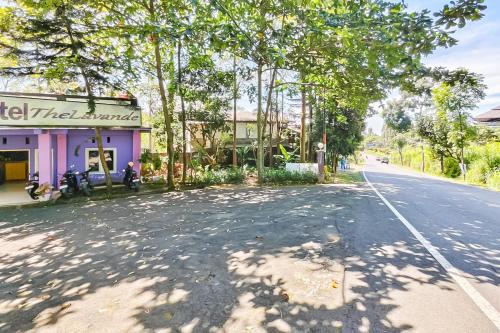 an empty street with trees and a purple building at RedDoorz near Kopeng Salatiga 