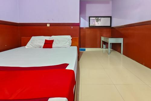 a bedroom with a bed with a red blanket and a table at RedDoorz near Kopeng Salatiga 