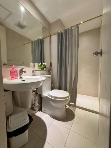 a bathroom with a toilet and a sink and a shower at Azure South by Dream Escapade in Manila