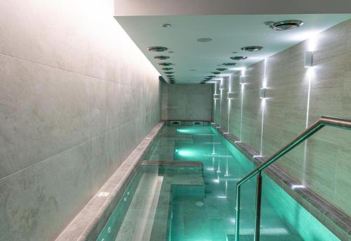 a swimming pool with green water in a building at Spa Hotel Persenk in Devin