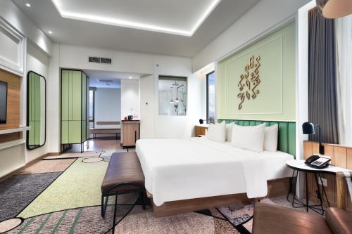 a bedroom with a white bed and a living room at Luwansa Hotel and Convention Center Manado in Manado