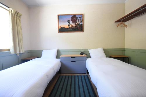 a room with two beds and a picture on the wall at Inn Between Waves in Shimoda