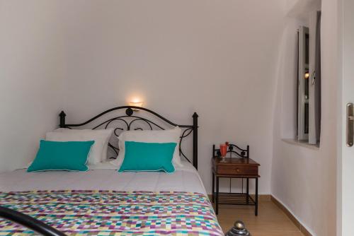a bedroom with a bed with two blue pillows at Sweet Pop in Fira