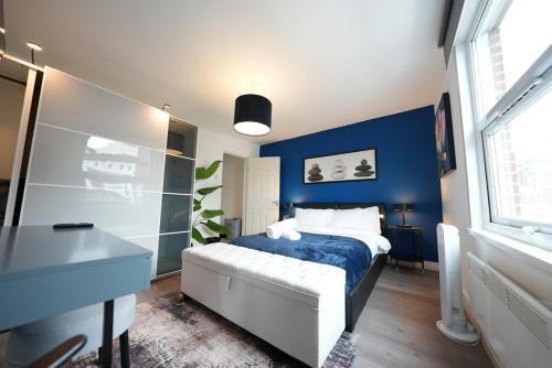 a bedroom with a bed and a blue wall at Cozy Urban Escape 2BR near Greenwich & Deptford in London