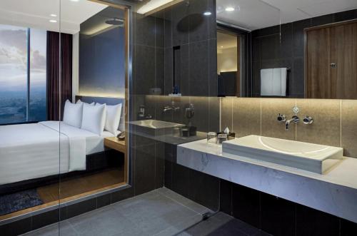 a bathroom with a bed and a sink and a mirror at Aston Sidoarjo City Hotel & Conference Center in Sidoarjo