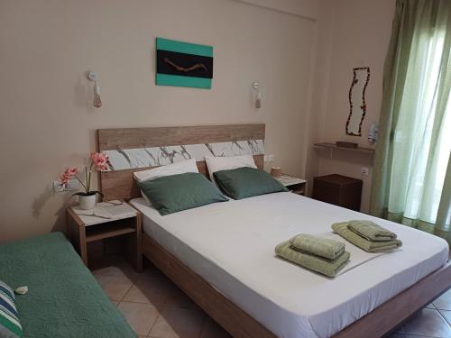 a bedroom with a large white bed with two green pillows at La MER Rooms Peraia in Perea