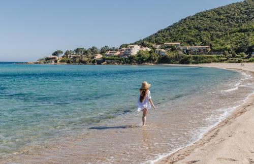a woman in a hat walking on the beach at Résidence le Télémaque in Conca