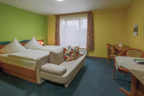 a bedroom with a bed and a table and a window at Hotel Ideal in Lübeck
