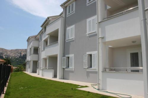 a row of white apartment buildings with a green yard at Apartments Crnekovic Tomislava 8 in Baška