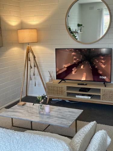 a living room with a tv and a table at Royal Park Retreat in Melbourne