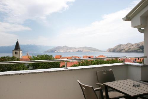a balcony with a table and chairs and a view of the water at Apartments Crnekovic Tomislava 8 in Baška