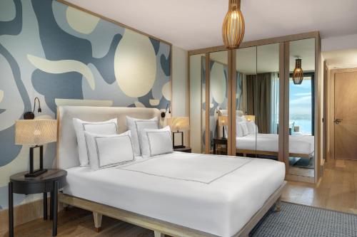 a bedroom with a large white bed and a mirror at Swissôtel Living Bodrum in Bodrum City