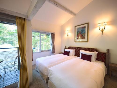 a bedroom with two beds and a balcony at Auberge de Primavera in Karuizawa
