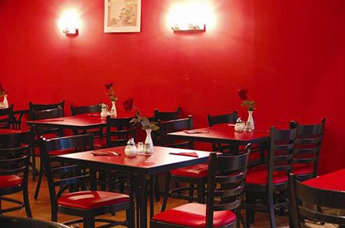 a restaurant with red walls and tables and chairs at Mini Himalaya Frankfurt City Messe in Frankfurt