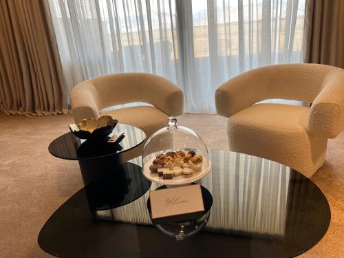 a room with two chairs and a table with a bowl of cookies at Hotel Aria in Podgorica