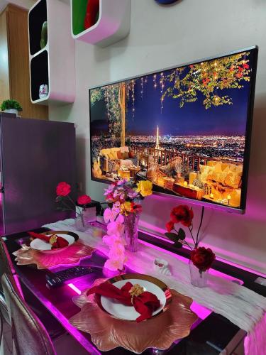 a desk with a computer monitor and a table with flowers at Staycation at Eastbay in Manila
