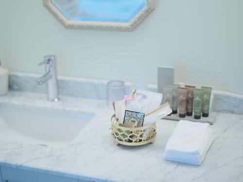a bathroom counter with a sink with a basket of books at Auberge de Primavera in Karuizawa