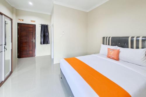 a bedroom with a bed with an orange and white blanket at Sans Hotel Bliss Pekanbaru in Sultan Syarif Kasim II International Airport