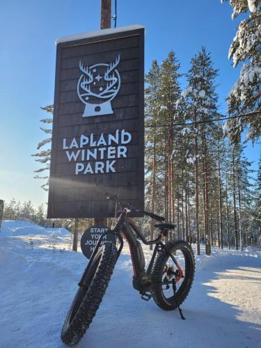 a bike parked in front of a sign in the snow at Lapland Winter Park Chalets in Rovaniemi