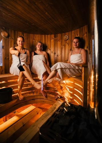 a group of three women sitting in a sauna at Lapland Winter Park Chalets in Rovaniemi