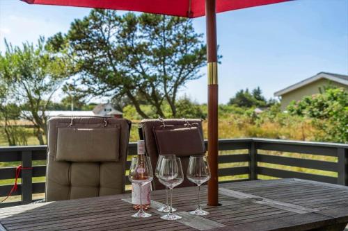 a wooden table with two wine glasses and an umbrella at 1353-Snedsted-Ebenezervej-24 in Snedsted