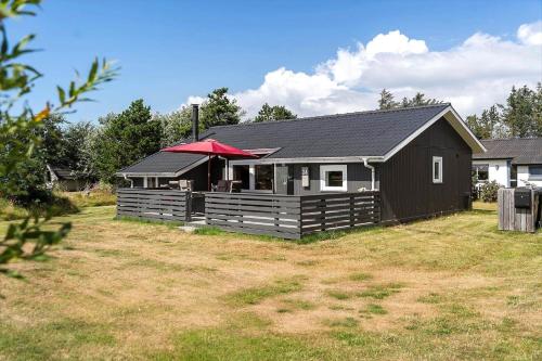 a black house with a red roof in a yard at 1353-Snedsted-Ebenezervej-24 in Snedsted