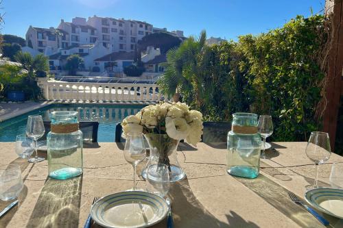 une table avec des verres et un vase de fleurs sur elle dans l'établissement Charming house with swimming pool and mooring, à Grimaud