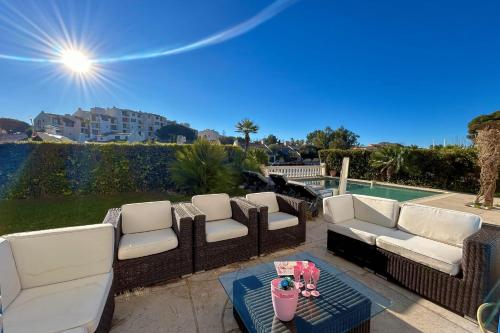 une terrasse avec des canapés blancs et une table avec un verre dans l'établissement Charming house with swimming pool and mooring, à Grimaud