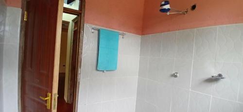 a bathroom with a shower with a blue towel at Mwea Farmstay -CampSite and Nature Trail in Karaba
