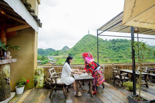 two women sitting at a table on a balcony at Lakeview Homestay Lo Lo Chai in Dồng Văn