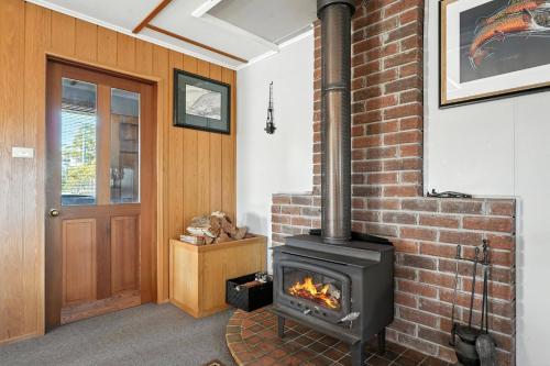 a fireplace in a room with a brick wall at Bull Tavern Cabin Cozy Lakeside Escape in Miena Tasmania in Miena