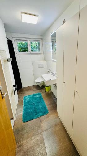 a bathroom with a white sink and a blue rug at Ferienhaus Waldklause in Schwarzenberg