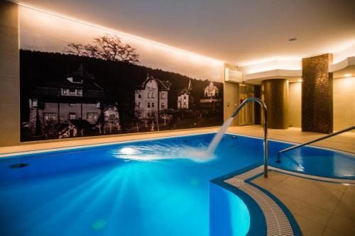 a swimming pool in a hotel with a painting on the wall at Spa & Wellness Vila Antoaneta in Lázně Luhačovice