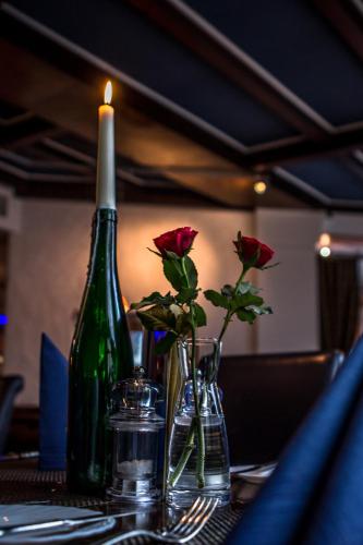 a candle and two roses in vases on a table at Hotel Blaue Ecke in Adenau