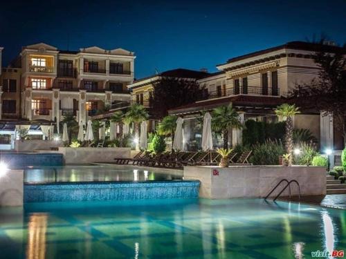 Una piscina frente a un edificio por la noche. en Green life private garden studio, en Sozopol