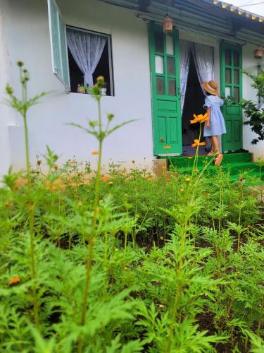 a woman standing outside of a house with a window at Poong's Garden Mộc Châu in Mộc Châu