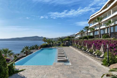 a resort swimming pool with chairs and umbrellas at Swissôtel Living Bodrum in Bodrum City
