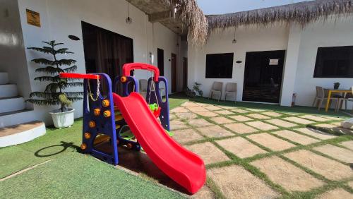 a playground with a red slide in a yard at Camotes Hostel Resort in Camotes Islands