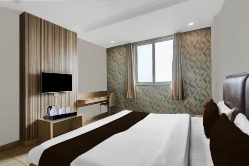 a hotel room with a bed and a television at Super Hotel O Haldwani Near Bus Stand in Haldwāni